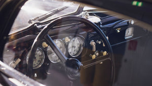 Black metal dashboard of a classic car with white gauges